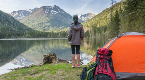 Woman looking over a lake with camping gear behind her